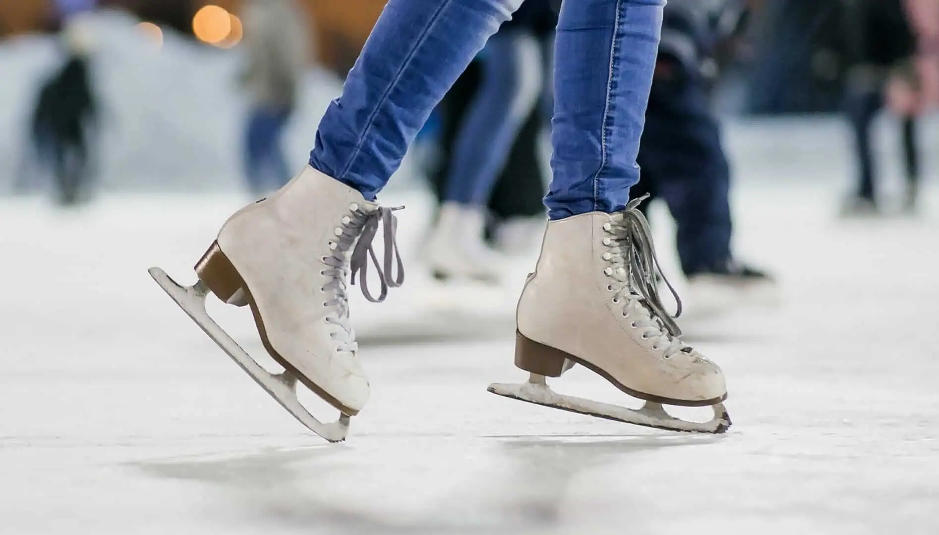Close up of a skater's white figure skates "walking" to the right on their toe picks - taking the next steps in skating