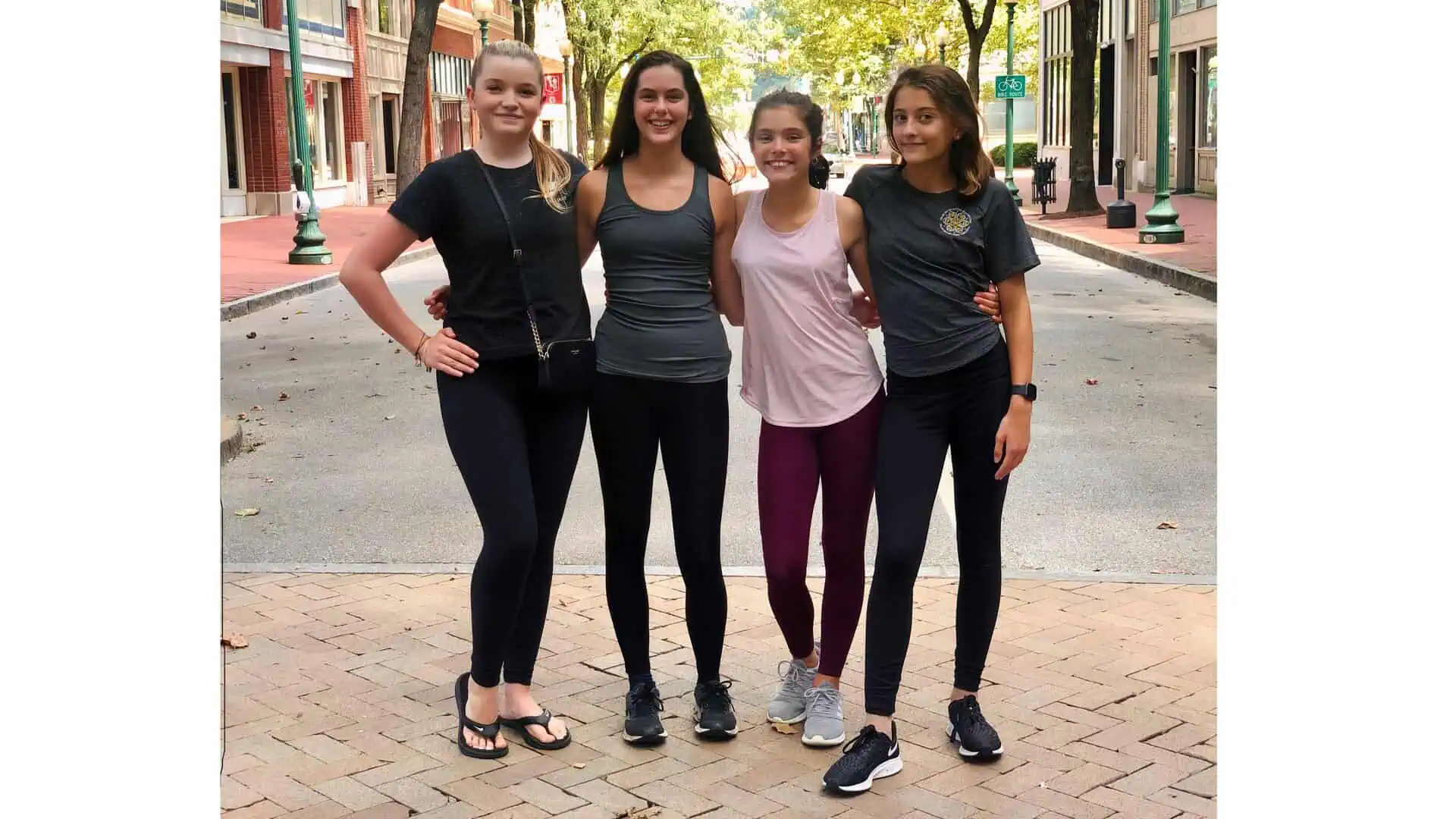 Four teens wearing a variety of figure skating practice outfits consisting of skating leggings and fitted shirts