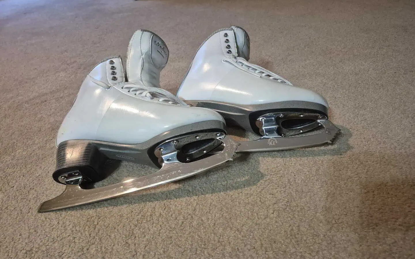 Close up of figure skating blades attached to white figure skating boots